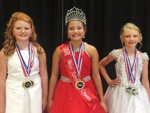 Jamboree Pageant: Ages 7-10. 2nd runner-up Madeline Cierra Stephens, Queen Isabella Faith Rackley, and 1st runner-up Leah Elisabeth Trapp