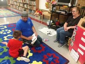 Raymond Lippart, III reading with his son Raymond Lippart, IV with mother Ashley Mooneyham looking on at Smithville Elementary School