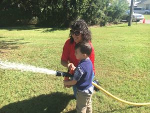 Smithville Volunteer Fire Department Shows Kids how to work the fire truck's water hose at Smithville Head Start Open House