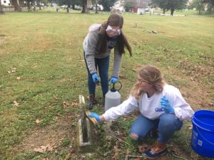 Katherine Gassaway and Zoe Cripps of Girl Scout Troop 750 cleaning tombstone at Smithville Town Cemetery Saturday