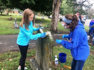 Jenna Wright and Katie Patterson of Girl Scout Troop 750 cleaning tombstone at Smithville Town Cemetery Saturday