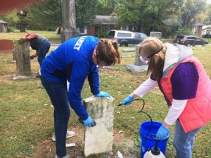 Darrah Ramsey and Emma Hancock of Girl Scout Troop 750 cleaning tombstone at Smithville Town Cemetery Saturday