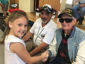 Elementary School student shakes hands with WWII veteran Edsel Frazier at past event