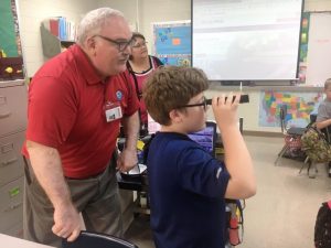 Civil Air Patrol Captain Steven Glover with Northside fourth grade student Ethan White who tries out a small telescope. LEAPS teacher Melissa Roysdon looks on.