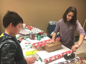 Child getting help wrapping his gift for parents during regifting event