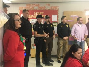 Smithville Head Start Director Cathy Shehane, Police Chief Mark Collins, Smithville Police Officers, and Mayor Josh Miller look on as children visit with Santa