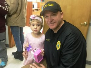 Smithville Police Chief Mark Collins presents bag of gifts to Harleigh a Head Start student