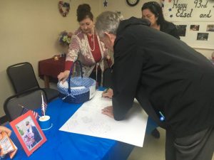 Family and friends sign huge birthday cards wishing Edward and Edsel Frazier a happy 93rd birthday