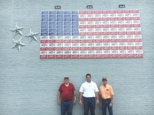 DeKalb County Clerk James L. (Jimmy) Poss with the help of Bill Neal (left) and Willard Brock (right) spent Memorial Day erecting a permanent display of the American Flag made of red, white, and blue auto license plates on the side of the DeKalb Title Building on the public square with permission of the owner Chris Cantrell. Poss came up with the idea and conducted the project at no cost to the county. Neal, a collector, provided the plates. Brock helped with the installation