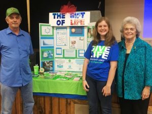 Abby Malone stands in front of her award winning 4-H interactive exhibit on transplants & organ donation with her grandparents, Dwayne and Barbara Cantrell