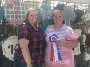 Fiddlers Jamboree Director of Crafts Dana Scott presents “Best Craft Display” Award to Misty Archer of Sassy South Art in Oxford, Alabama, manufacture of door hangars and front door decor