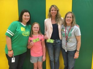 Northside Elementary Principal Karen Knowles (left) and Assistant Principal Beth Pafford (right) present the first “Eagle Bucks” of the year to student Liliana Judkins and Teacher of the Month Kristen Van Vranken