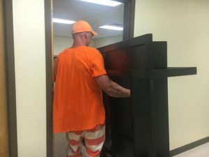 Supervised inmate from the DeKalb County Jail helps move furniture from the Chamber office in the Courthouse to a new location in the County Complex