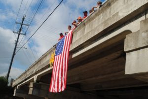 Local firefighters last year greeted motorcycle riders with waves and a huge American flag from the Veteran’s Memorial bridge on College Street overlooking the route below on Broad Street.