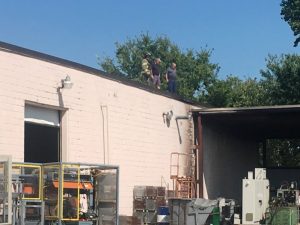 Smithville Firefighters and others stand on top of the Kingston factory surveying the scene after extinguishing a small fire outside the building Monday.