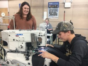 Amanda Callis, Plant Manager of 620 Pelham, Inc (formerly Omega Apparel) with employee Brittney McCardell who is shown sewing button holes on the Broadfall pants for the US Navy