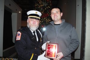 Smithville Fire Department Lieutenant Kevin Adcock presents plaque to Chad Driver of Wilson Bank and Trust for winning 3rd place Float in the Smithville Christmas Parade Saturday evening