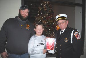 Smithville Fire Department Lieutenant Donnie Cantrell presents plaque to Justin Braswell and Kollin Young of the DeKalb County Junior Pro Football program for winning the “Spirit Award” by the Smithville Business and Professional Women’s Club for their entry in the Smithville Christmas Parade Saturday evening