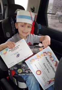 Head Start student Bucksley Haney receives his diploma, cap, and perfect attendance certificate during drive through Head Start Graduation Wednesday