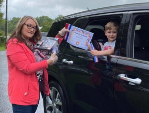 LBJ & C Smithville Head Start Director Cathy Shehane presents ribbons and certificate to head start student Bucksley Haney during Drive Through Head Start Graduation Wednesday