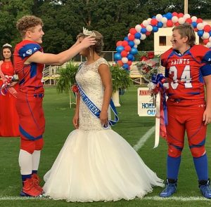 The 2020 DeKalb Saints Homecoming Queen Annabella Eleni Dakas was crowned Thursday night. Dakas, an 8th grader, was escorted by her brother Andrew Dakas (left) 8th grade captain, wide receiver and linebacker and Wesley Kent (right), 8th grade captain, running back and linebacker.