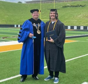 Lindsey Wilson College President Bill Lucky presents Eli Cross his degree in business administration.. Cross plans to begin working toward a Masters Degree at the school