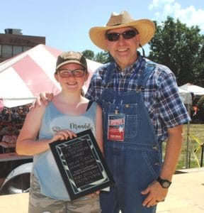 Fiddlers Jamboree President and Coordinator Sam Stout presents Reagan Brown of Springfield the Nolan Turner Memorial Entertainer of the Year award in the National Championship for Country Musician Begineers. The honor is presented to the best overall instrumental entertainer among winners in the dobro guitar, mandolin, five string banjo, and flat top guitar competition. Brown won the Dobro Guitar competition, received second place in the Mandolin category, and Third Place in both the Five String Banjo and Flat Top Guitar Contests.