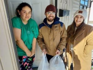 Jim Sherwood (center) and Osiris Mancera (right) deliver Christmas Eve meal to the home of Luminosa Galvan on behalf of the DeKalb Emergency Services Association