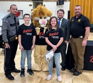 DeKalb West School student Levi Reynolds was the top essay winner overall during the D.A.R.E. Graduation Thursday. General Sessions/ Juvenile Court Judge Brandon Cox presented Reynolds with a $50 gift card. Hailey Brown (not pictured) was the winner from Ms. Jeanna Caplinger’s homeroom. Sophia Caraway had the best paper in Ms. Rachel Desimone’s homeroom. Also pictured DA.R.E. Instructor and SRO Billy Tiner of the DeKalb County Sheriff’s Department, DAREN the Lion (D.A.R.E. mascot) and Sheriff Patrick Ray