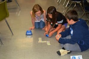 Pictured left to right are Lileigh Smith, Savannah Stanley, and Waylon Ellis who are learning how to design an obstacle course or pathway by creating a computer code for the Botley coding robots to maneuver.