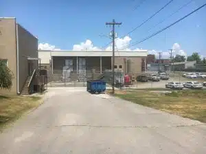 Photo shows rearview of a portion of the DeKalb County Jail Annex from East Webb Street. Veterans building pictured to the left. The driveway leading to the dumpster and fence was once a city street which was closed for the jail annex expansion to take place in 2001