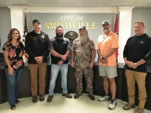 A popular and colorful character from the Duck Dynasty reality television series which aired on A&E from 2012 to 2017 is making his home in Smithville. Tim Guraedy, best known to the show’s millions of hard-core fans as “Mountain Man,” was invited to the monthly meeting of the Smithville Mayor and Aldermen Monday evening to offer the opening prayer. Pictured left to right: Alderman Beth Chandler, Police Chief Mark Collins, Mayor Josh Miller, Mountain Man Tim Guraedy, County Commissioner/ Local businessman Tony Luna, and School Board member Jim Beshearse