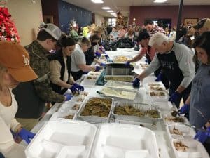 A host of people filling the food serving trays