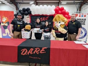 Sixth graders at DeKalb Middle School graduated from the D.A.R.E. (Drug Abuse Resistance Education) program in a ceremony Friday. Pictured from left are DMS School Resource Officer and D.A.R.E. Instructor Joseph Carroll, 1st Place Essay Winner – Jackson Longmire, 2nd Place – Nevaeh Knight, 3rd Place – Sophia Pina, Darren the D.A.R.E. Lion mascot, and Sheriff Patrick Ray (Shawna Willingham Photo)