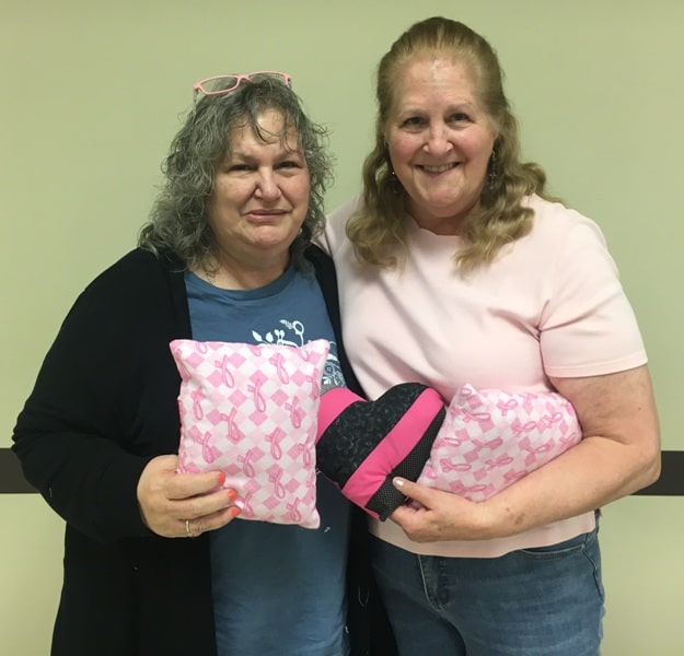 FCE members and breast cancer survivors Bea Garrison and Jenny R. Reichenbach with comfort cushions made by members of the local FCE Club to be donated to a breast cancer clinic and dispersed to future patients.